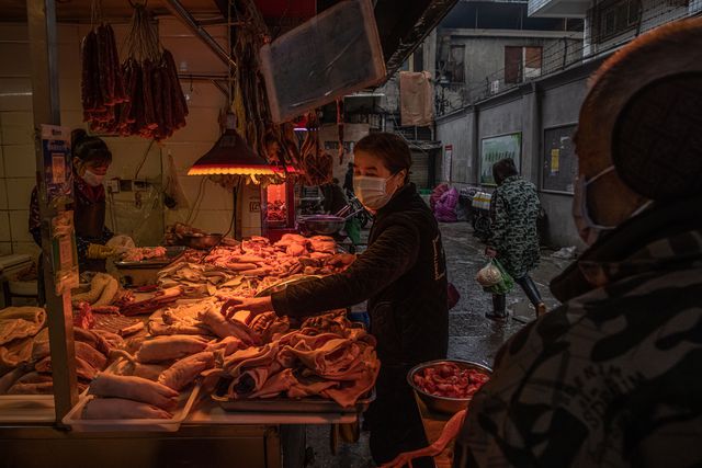 A woman wearing a protective face mask choses meat at a market in a residential area, in Wuhan, China, January 22nd, 2021.